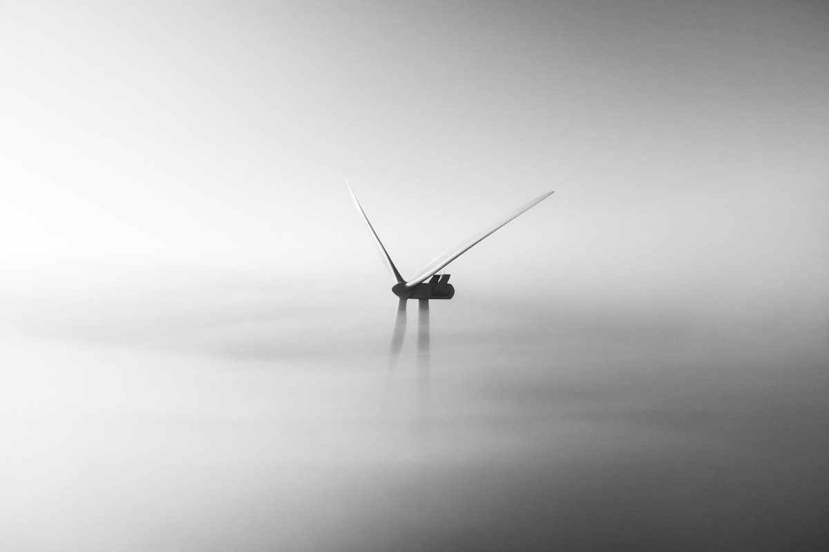 A lone windmill blade in a misty expanse, evoking quiet perseverance